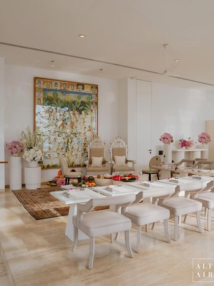 The indoor space for Radhika and Anant's ceremony was designed to be modern, minimal, and spiritual. We used a neutral palette with pops of pink florals and elegant, high-backed chairs for the main family seating.