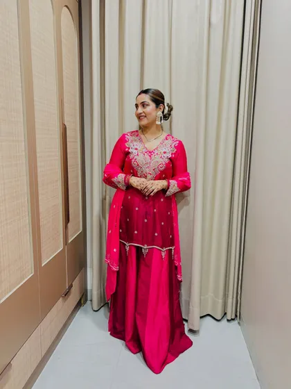 The same pink sharara suit, with the dupatta draped differently. This shows the versatility of a single outfit. The hair is in a neat bun with a gajra for a traditional touch.