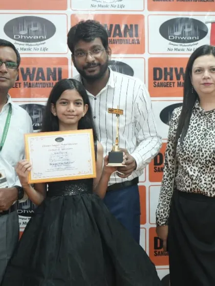 A student, her mother, and teachers pose together with her well-deserved trophy.