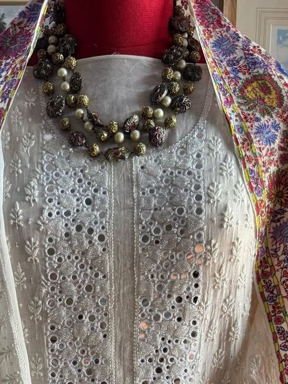 The off-white mirrorwork suit styled with a contrasting colorful dupatta, showcasing its versatility.