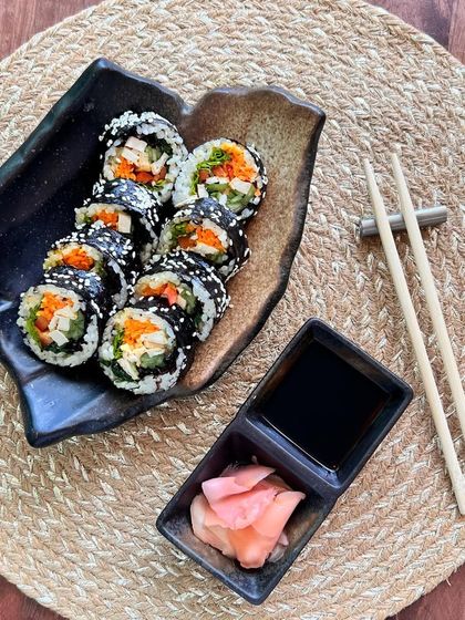 A serving of Korean Gimbap with soy sauce and pickled ginger, ready to be enjoyed.