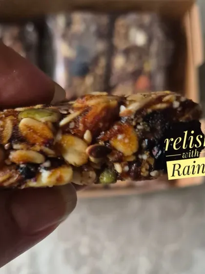 A close look at one of my homemade Granola Bars. It's packed with rolled oats, various nuts, seeds, and dried fruits, all bound together. This version is sweetened naturally with dates.
