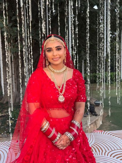 A full shot of Aashna looking absolutely radiant in her red Seema Gujral lehenga, ready for her wedding ceremony.
