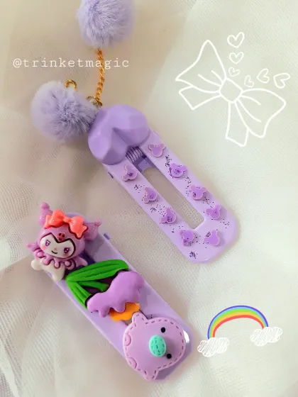 A closer look at my purple-themed hair clips. This pair features cute character charms and fluffy pom-poms, bringing a playful and magical vibe to your accessory collection.