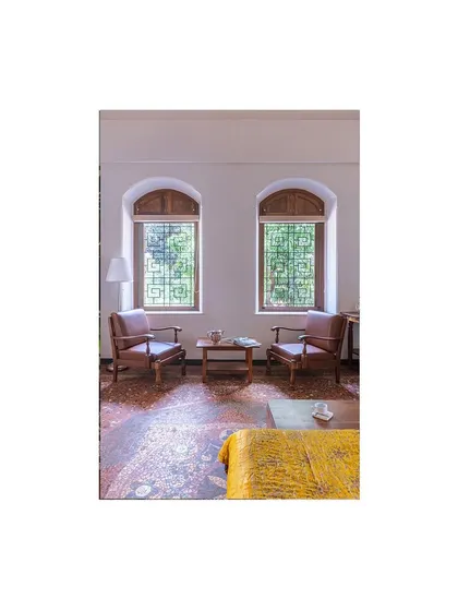 The restored bedroom, where newly designed solid wood windows with traditional geometric grills complement the original mosaic flooring. We salvaged wood from the old false ceiling to craft these new elements.