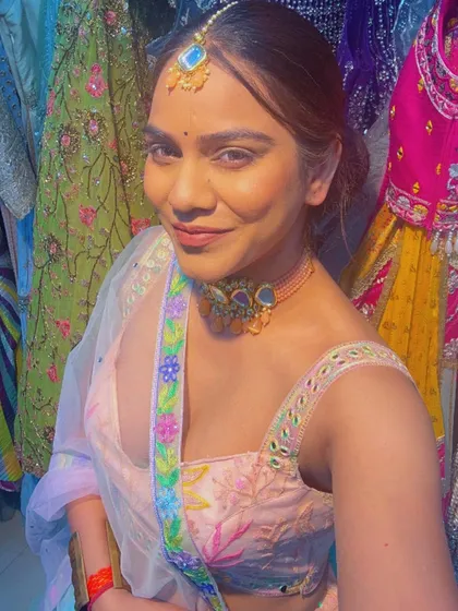A selfie of a client trying on a playful rainbow tulle lehenga with a delicate embroidered blouse. Perfect for a fun, modern festive look.