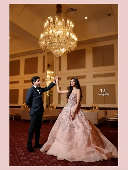 A wider angle of the couple's dance, showcasing the grandeur of the ballroom and the beautiful chandelier. This is a classic, elegant wedding portrait.