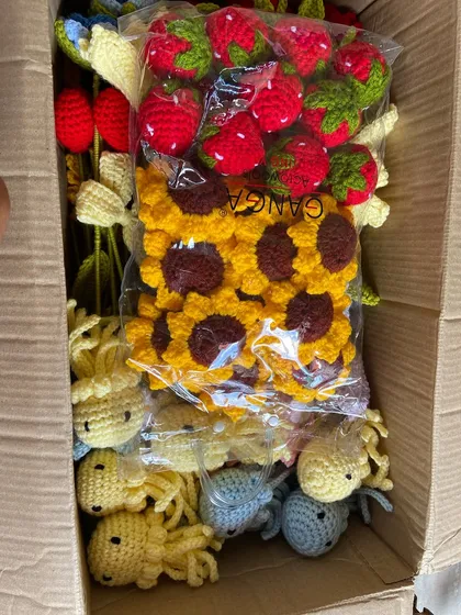A box packed with a mix of amigurumi jellyfish, strawberries, and sunflower keychains.