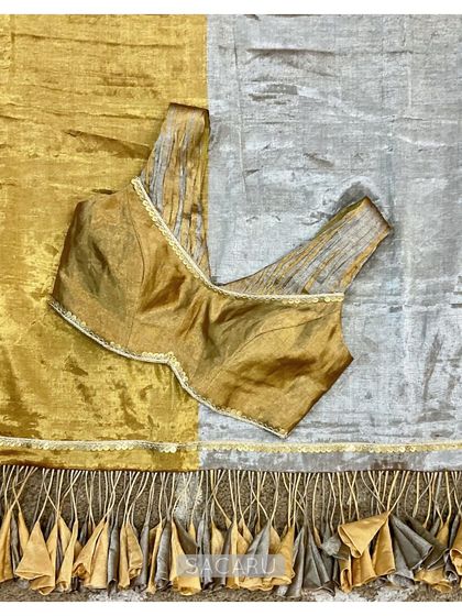 A stunning gold and silver tissue saree with dramatic tassels, paired with a chic sleeveless, ruched blouse with metal sequin accents.