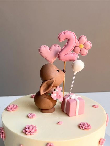 A detailed look at the adorable bunny topper, with its quilted texture and sweet expression, surrounded by heart and flower-shaped balloons.