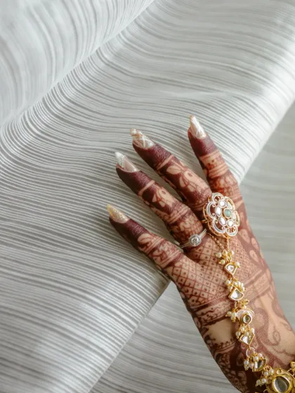 A close-up of the bride's hand, adorned with beautiful henna and a statement hath phool. I focus on these details to capture the full artistry of the bridal look.