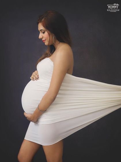 A simple and elegant studio portrait. The white fabric wrap creates a beautiful silhouette, focusing all the attention on the lovely baby bump.