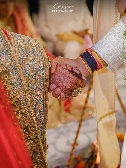 A close-up of the couple holding hands during the ceremony. This simple gesture symbolizes their union and the beginning of their shared life, with every detail of their attire adding to the richness of the moment.