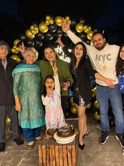 A happy family celebrating a 32nd birthday on the terrace with a cake and our balloon backdrop.
