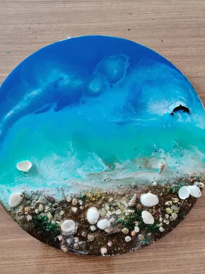 This is the stunning result of our beginner-friendly Resin Ocean Art workshop. Participants learn to mix pigments and pour resin to create these beautiful, glossy ocean scenes complete with real shells.