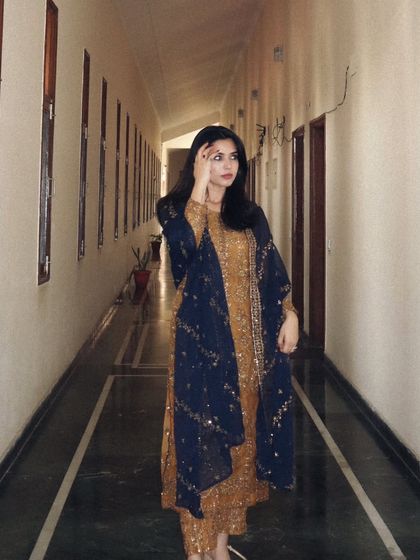 A candid, thoughtful pose in the mustard and blue ethnic wear. This adds a touch of personality and storytelling to the fashion shot.
