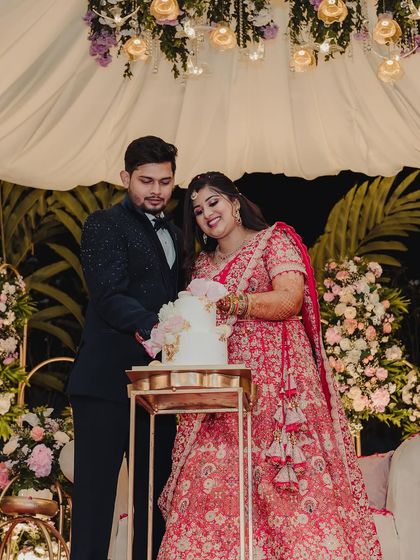 A sweet moment蛋糕 cutting for Bhumi and Avi at their reception. The stage, draped in soft fabrics and adorned with a canopy of flowers, provided a beautiful and romantic backdrop for their celebration.