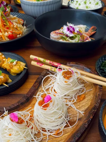 An artful presentation of rice noodles alongside other Thai delicacies, showcasing the diverse textures and flavors of our 'Bangkok Joes' menu.
