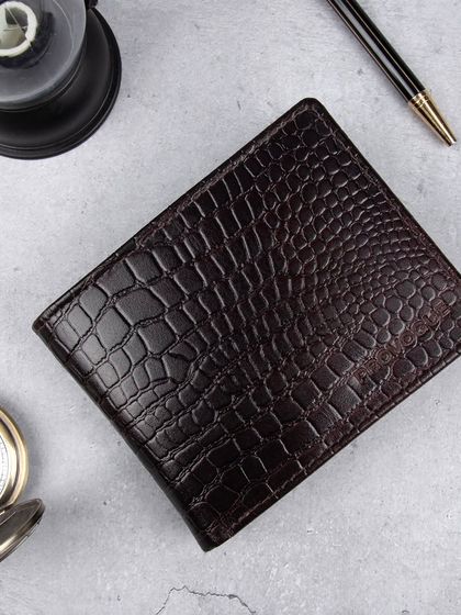 A styled flat-lay of the dark brown crocodile wallet.