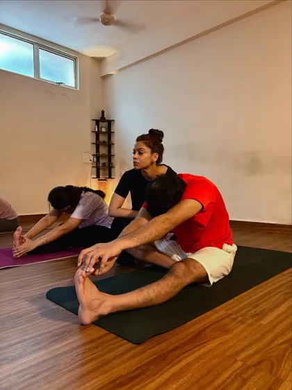 Offering a gentle adjustment in Paschimottanasana (Seated Forward Fold). This helps the student to fold from the hips and protect his lower back.