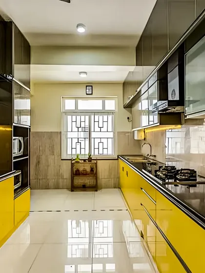This parallel kitchen layout makes a bold statement with its vibrant yellow high-gloss cabinets. The sleek black countertop and reflective flooring create a striking contrast, while the layout itself maximizes efficiency and storage in a galley-style space.