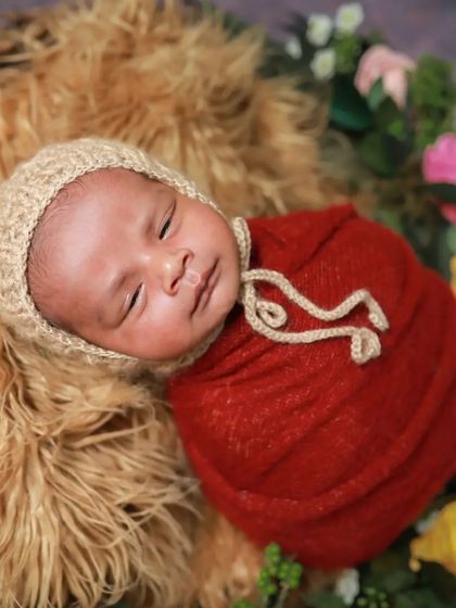 All wrapped in red and ready for a nap. This little one looks so cozy in this furry basket surrounded by flowers.