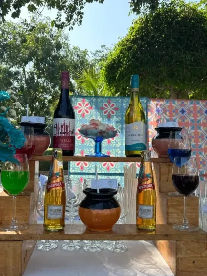 A colorful outdoor bar setup perfect for a daytime event. The display features a mix of wines, beers, and colorful cocktails, arranged on a rustic wooden pallet stand.