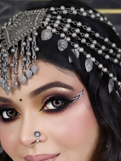A close-up of a model's eye makeup, complemented by a unique oxidised silver mathapatti with leaf-shaped danglers.