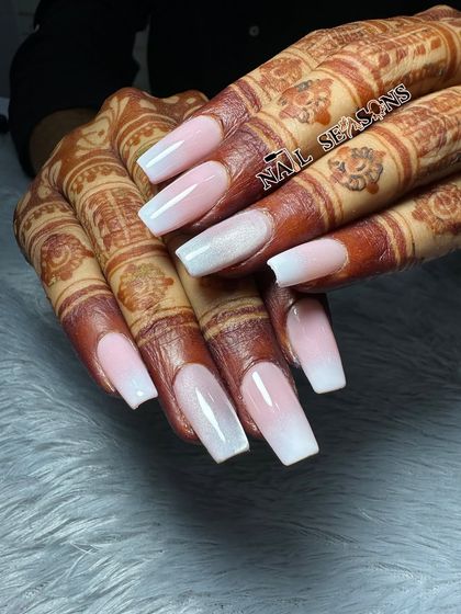 A classic and elegant choice for a bride. These long, square-shaped nails feature a soft pink and white ombre, which looks stunning with her mehndi.