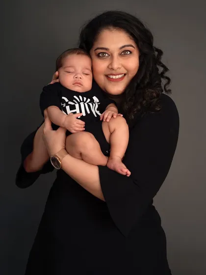 A mother's gentle hold. This portrait of a mom smiling while her newborn sleeps on her shoulder is a beautiful representation of the maternal bond.