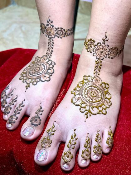 A minimalist foot design featuring a central mandala connected to a floral anklet, with delicate leafy patterns on the toes.