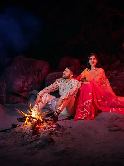 Dressed in ethnic wear, the couple shares a moment by the bonfire. The mix of traditional attire and the raw, fiery element creates a unique and visually striking pre-wedding photograph.