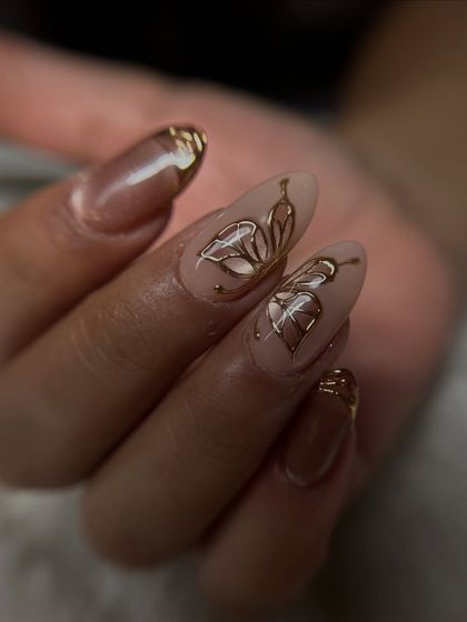 A side view of the golden butterfly nail art, showing the delicate lines and the shimmer of the cat-eye base.