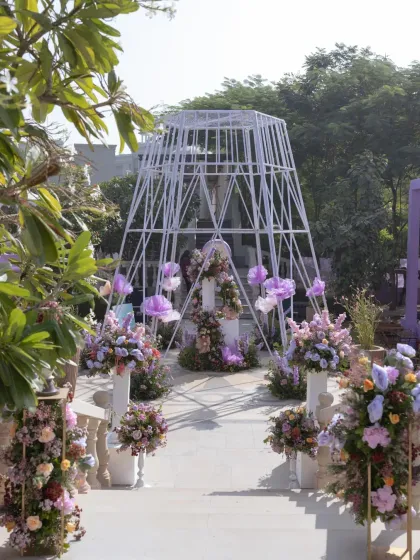 The entrance to the 'Fiesta Siesta' carnival, framed by a modern white structure adorned with lavender florals, setting a whimsical and elegant tone.