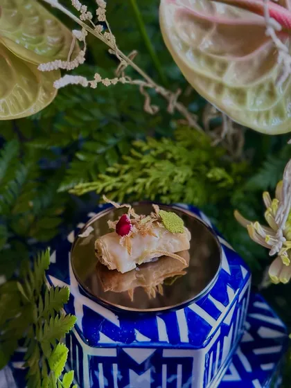 A Truffle Asparagus & Edamame Éclair, elegantly presented on a geometric blue and white stand. This appetizer is a perfect example of our creative and sophisticated small plates.