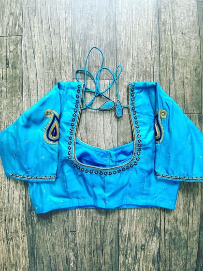 This light blue blouse has a simple bead border and two paisley motifs on the sleeves. It's a great example of minimal but effective design.