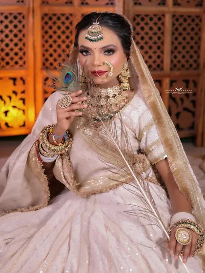 A seated portrait with the bride holding a peacock feather, adding a touch of royalty and symbolism.
