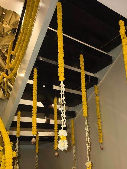 A staircase decorated for Diwali with hanging garlands of marigold and jasmine flowers, creating a festive look.