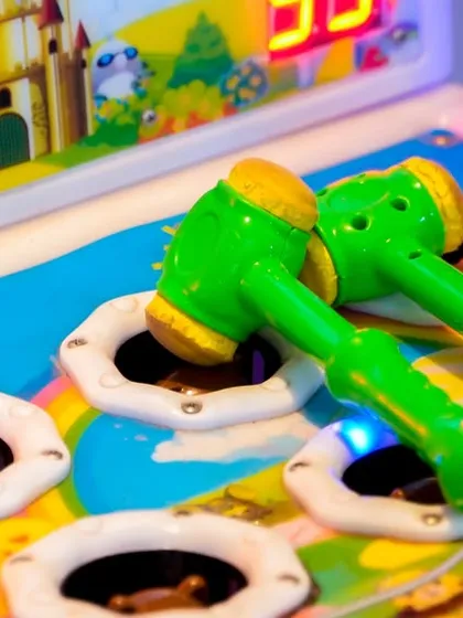 A close-up of the 'Whac-A-Mole' game, showing the soft hammers and colorful setup that appeals to younger children.