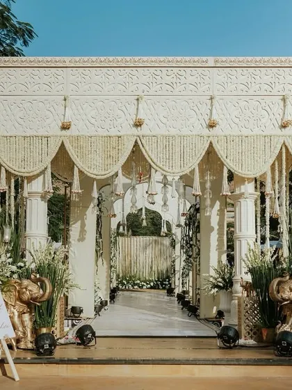 The entrance to Aashvi and Akash's 'Ivory Clad Promises' wedding. The grand structure, draped in ivory and adorned with traditional floral tassels, created a serene and stately welcome for the guests.