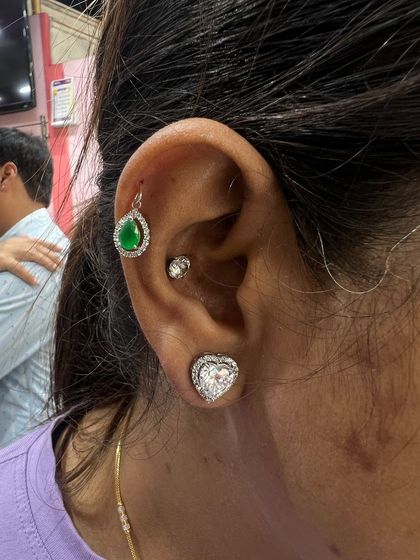 This look combines a bold emerald green hanging with a large heart-shaped lobe stud, showing how to pair statement pieces together for a dramatic effect.