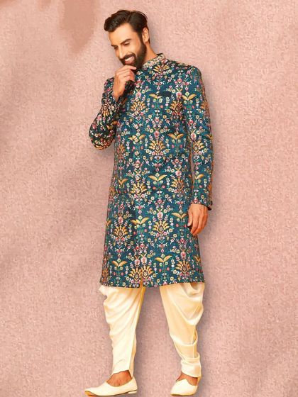 A side profile of the beautiful teal sherwani, showing how the pattern flows across the entire garment. Paired with cream dhoti pants, it's a balanced and stylish look.