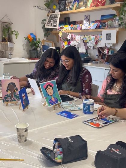 Two women admiring their Frida Kahlo-inspired portraits during a guided painting session.
