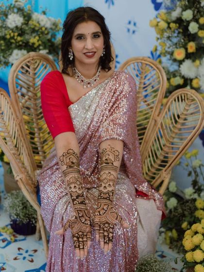 The beautiful bride posing with her architectural-themed mehendi, looking radiant in her sequined saree.
