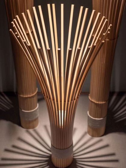 This floor lamp is a true statement piece, crafted from radiating bamboo slats that create a fan-like structure. The light source at the base illuminates the bamboo from within, casting dramatic shadows and highlighting the natural beauty of the material.