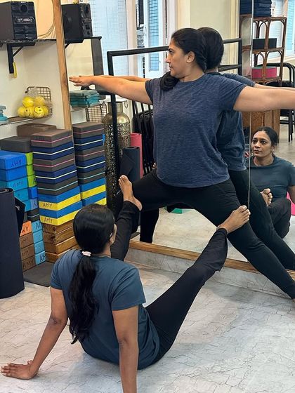 Another pair works on the Warrior II alignment drill, demonstrating how partner work is integrated into our regular classes.