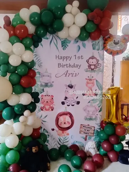A classic jungle theme birthday decoration for a first birthday, with a cute animal banner and a green and brown balloon arch.