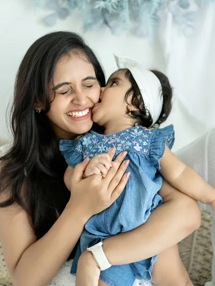 A sweet kiss for mommy. These candid moments of affection are what make family portraits so special and heartwarming.