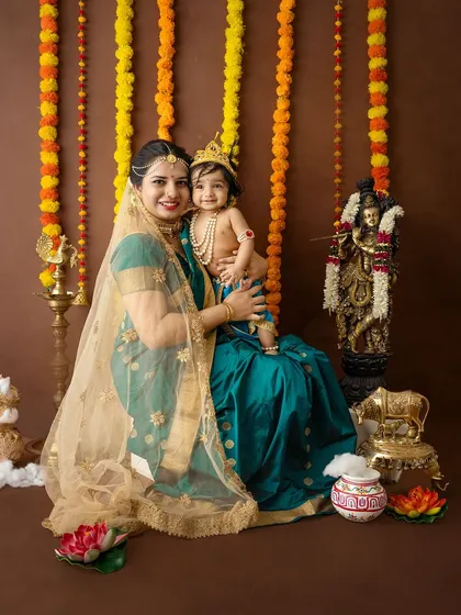 A classic portrait of a mother and child in their Janmashtami attire, smiling warmly for the camera.