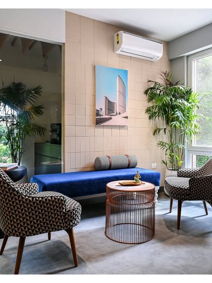 This informal seating area within the manager's cabin uses a mix of patterned armchairs and a simple blue daybed against a textured tile wall.